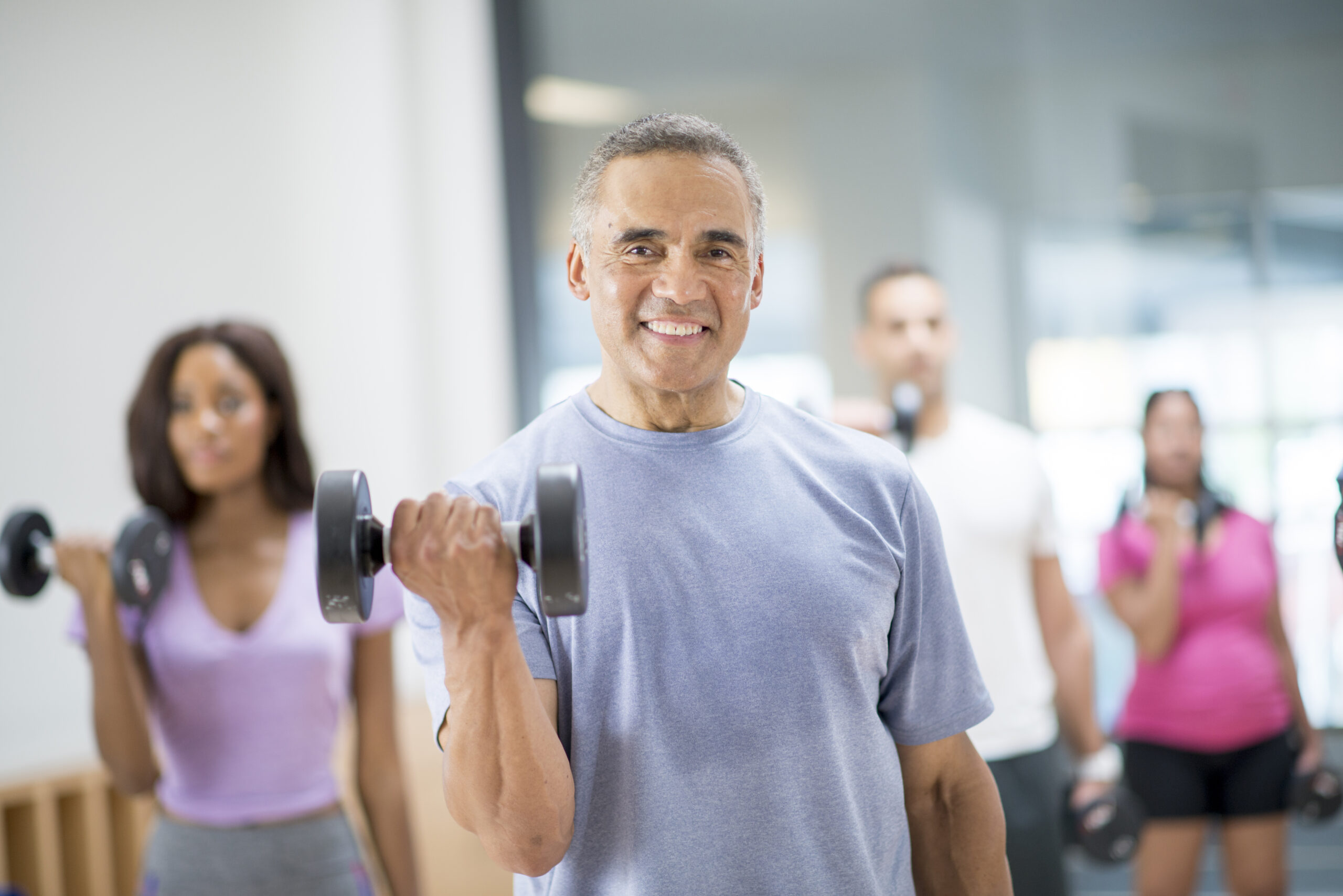 Group exercise class lifts dumbbells and smiles
